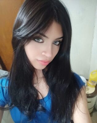 Woman with long dark hair and blue top looking at the camera in a close-up shot.